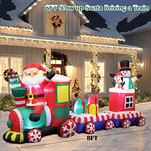 Inflatable Santa driving a train with snowman, Christmas decoration in front of house.