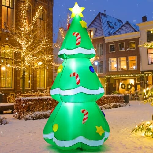 Inflatable Christmas tree with lights and snow in a decorated town square.
